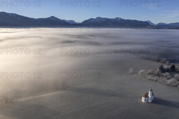 Aerial view of a chapel in front of mountains in winter, hoarfrost, morning light, fog, view of the Bavarian Alps, Sankt Johannisrain, Alpine foothills, Bavaria, Germany, Europe