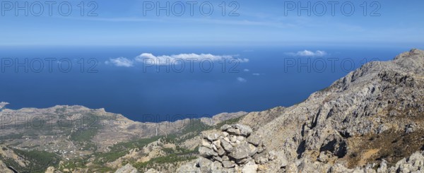 Behind the rocky promontory of the summit of Kali Limni, the bright blue sea of the west side of Karpathos spreads out, interspersed with clouds, hike to the summit of Kali Limni, Kali Limni, Lastos, Karpathos, Greece, Europe