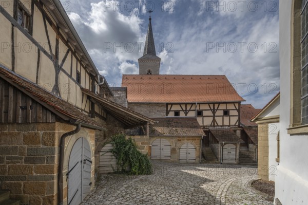 Former so-called Kirchgaden, barns in the historic fortified church, behind the tower of the church of St John the Baptist, Hüttenheim, Lower Franconia, Bavaria, Germany, Europe