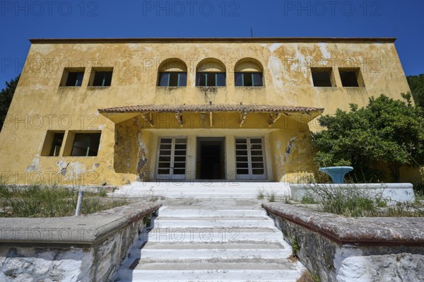 An abandoned building with a crumbling façade and an external staircase on a sunny day under a blue sky, Lost Place, Former Santorium, Tuberculosis Centre 1947-1970, Former Italian Colonial Settlement, Eleousa, Campochiaro, Rhodes, Dodecanese, Greek Islands, Greece, Europe
