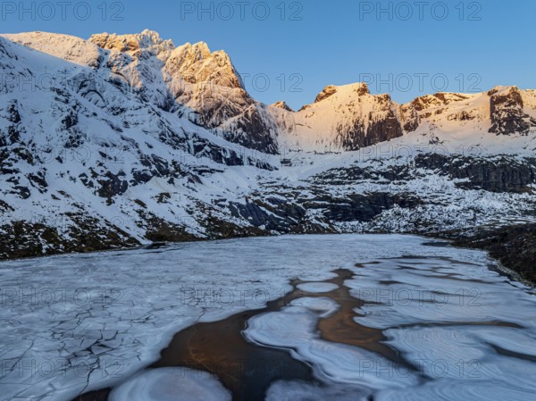 Aerial view of icy lake in front of steep mountains, winter, sunrise, Storvatnet, Flakstadoya, Lofoten, Norway, Europe