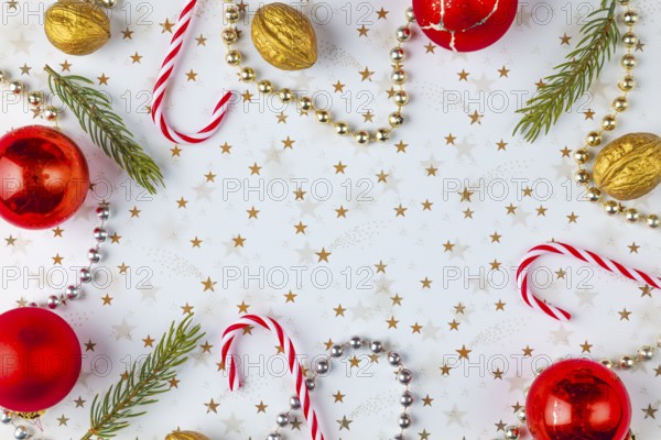 Frame made of Christmas decorations, fir branches, baubles, nuts on a white background with golden stars, copy room