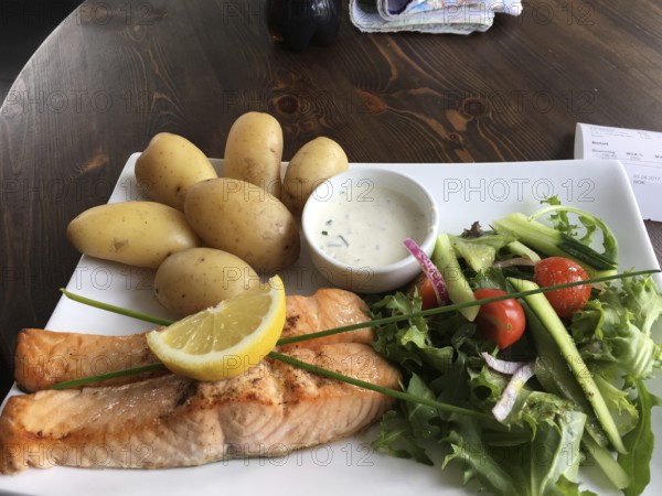 Grilled salmon with potatoes and fresh salad, served on a wooden table in rustic style, Norwegian food, Norway, Europe