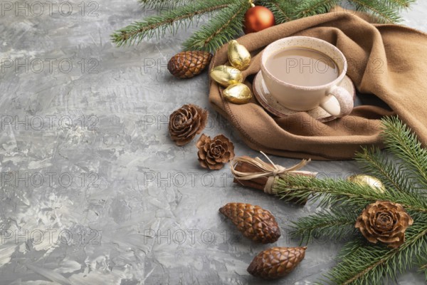 Christmas or New Year composition. Decorations, cones, cinnamon, fir and spruce branches, cup of coffee, wool scarf on a gray concrete background. Side view, copy space