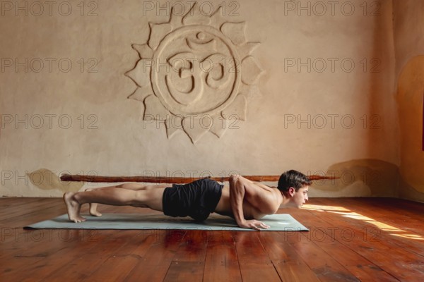 Profile of young athlete doing shoulder exercises in yoga studio, push-ups, chaturanga dandasana (four limbed staff pose), surya namaskar, sun salutation complex