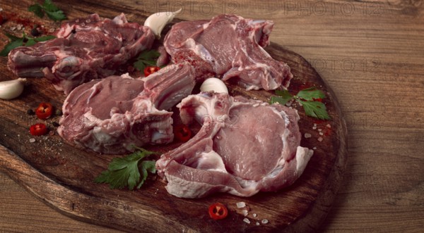 Raw calf meat, meat on the bone, meat for barbecue, cutting board, with spices and herbs, top view