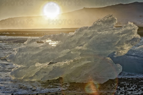 Backlit block of ice, beach at glacier lagoon Jökulsarlon, Breiðamerkursandur, south coast, Iceland, Europe