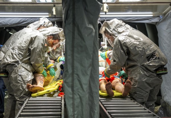 Decontamination of injured persons after an assumed accident involving hazardous substances, fire brigade and aid organisations practise setting up and operating a decontamination station, injured persons are sighted and then washed in a special shower tent to remove possible hazardous substances and chemicals in order to avoid further injuries, the emergency services wear special, ventilated protective suits, large-scale exercise by the Essen fire brigade