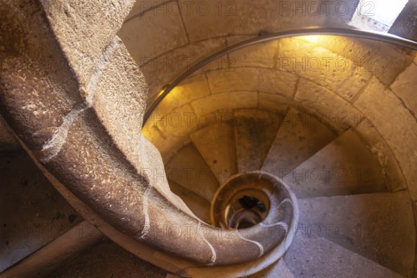 Warm light illuminating ancient stone spiral staircase descending into the depths of barcelona cathedral, a captivating architectural marvel