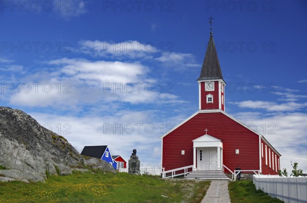 Red church with white entrance and tower, sculpture next door under a blue sky, Church of the Saviour, old town of the capital of Greenland, Nuuk, Greenland, Denmark, North America