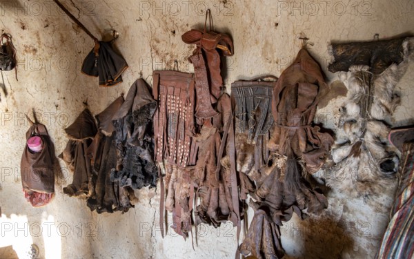 Various traditional leather aprons hanging on the wall, interior of a mud hut of the first woman in a Himba village, near Opuwo, Kaokoveld, Kunene, Namibia, Africa