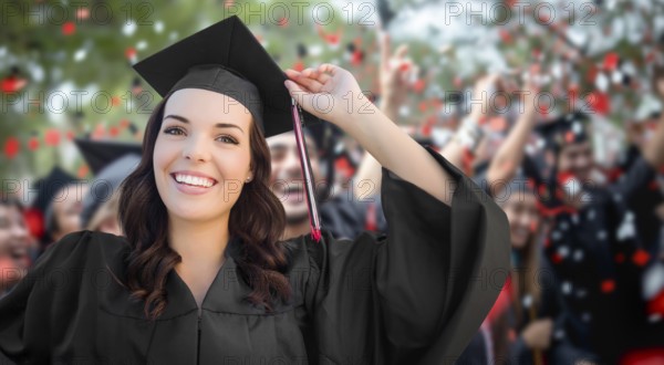 Young female graduate celebrating her graduation with her fellow classmates outdoors
