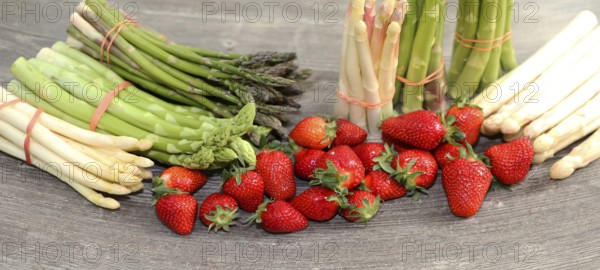 Green asparagus, white asparagus and fresh strawberries decorated on a rustic wooden table