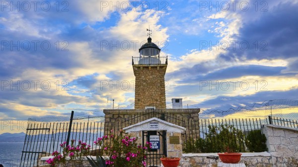 An old lighthouse overlooked by a dramatic sky at sunset, surrounded by flowers, lighthouse, Cape Melagkavi, Gulf of Corinth, Corinth, Peloponnese, Greece, Europe