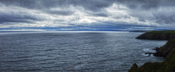 Gloomy panorama of the coast under a heavy, cloudy sky, Waterford Coast