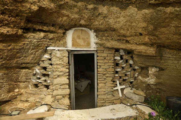 Entrance to a cave carved into the rock, surrounded by a stone wall, with a cross and plants on the sides, rock church of Agios Nikolaos, Oasis Beach, Kallithea, Rhodes, Dodecanese, Greek Islands, Greece, Europe