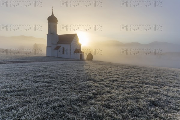 Chapel at sunrise in front of mountains, sunbeams, backlight, hoarfrost, Sankt Johannisrain, Alpine foothills, Bavaria, Germany, Europe