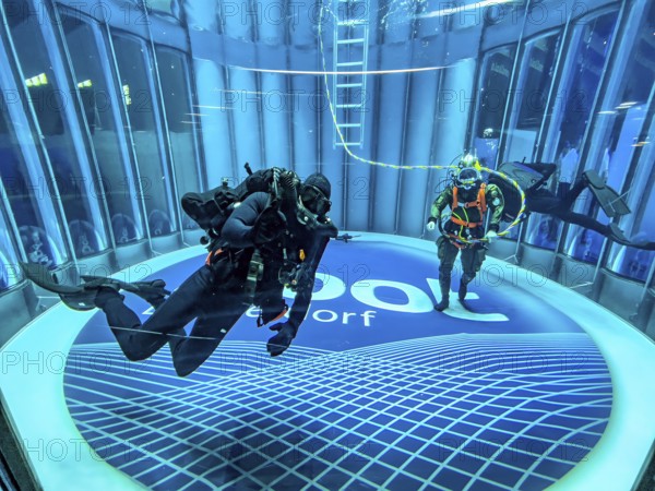 View into diving tower of Messe boot Düsseldorf, on the left recreational diver, on the right helmet diver with hose for air supply from outside the water, on the ground logo and lettering of Messe boot, Düsseldorf, North Rhine-Westphalia, Germany, Europe