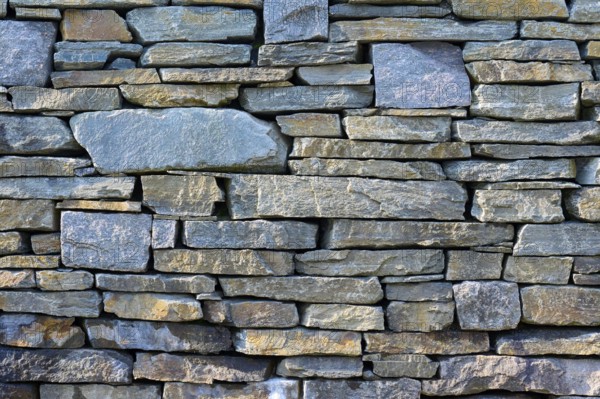 Large, irregular natural stones in various shades of grey form a rustic stone wall, Bergen, Vestland, Norway, Europe