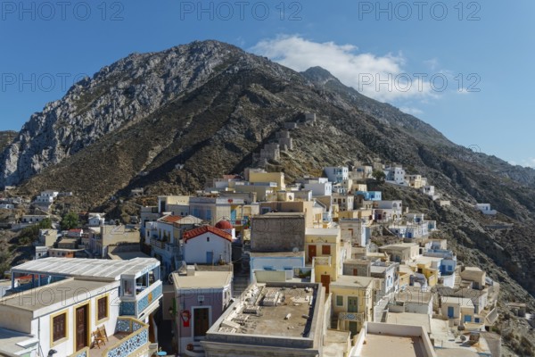 Colourful houses of the picturesque village of Olymbos spread out on a mountainside under a clear blue sky, Olymbos, Karpathos, Greece, Europe