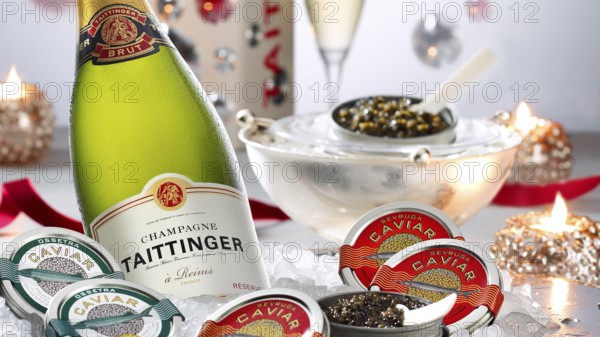 Champagne bottle, caviar, caviar tins, decorated with burning candles, studio shot