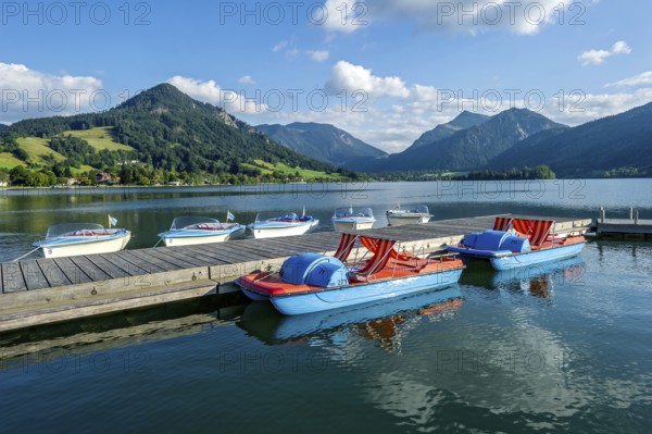 Electric boats and pedal boats at jetty, boat hire, Markt Schliersee, Schliersee, behind mountains Brecherspitz or Spitzing and Schlierseespitz, Mangfall mountains, Bavarian Prealps, Upper Bavaria, Bavaria, Germany, Europe