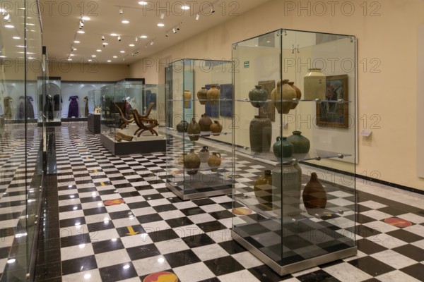 Interior of city museum, Campeche city, Campeche State, Mexico display cabinets of pottery and furniture