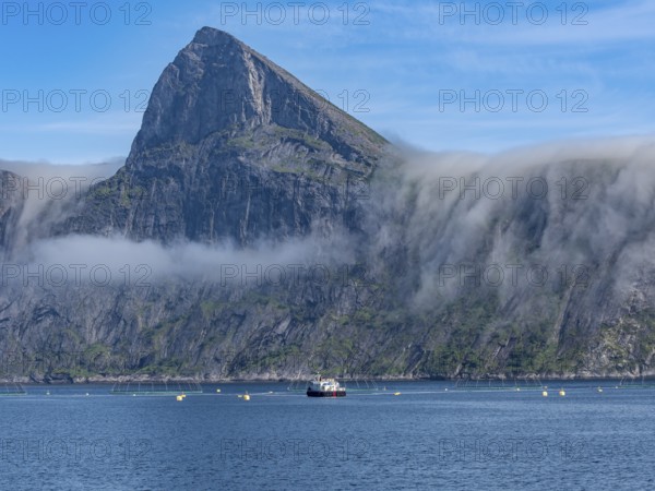 Salmon farm, aquaculture in the Mefjord on Senja island, in the background the peak of famous Segla mountain, Norway, Europe