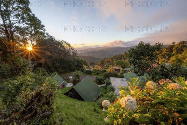 Cabins of a lodge in the cloud forest, in the evening light, Paraiso Quetzal Lodge, view over mountain landscape, sun star, San José province, Costa Rica, Central America