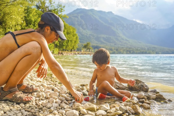 Mother and son enjoying quality time together, playing with pebbles and toy cars on the scenic shores of lake bohinj in slovenia