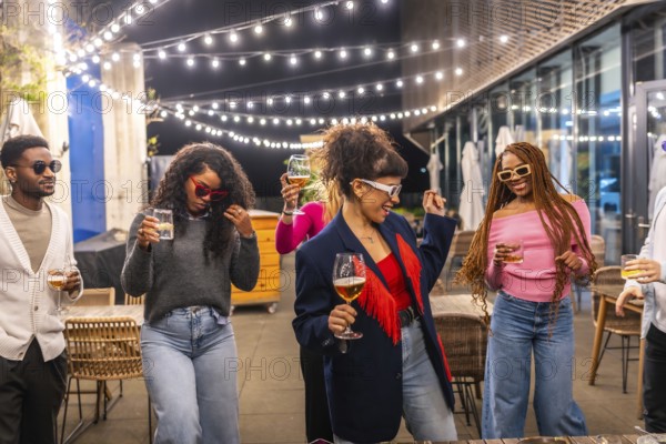 Group of young multi-ethnic friends dancing and drinking at outdoor night party