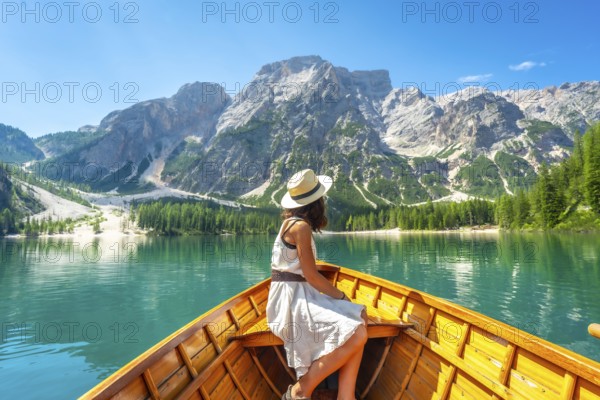 Young woman admiring the stunning landscape of lake braies from a wooden rowboat, surrounded by majestic mountains and crystal clear turquoise water