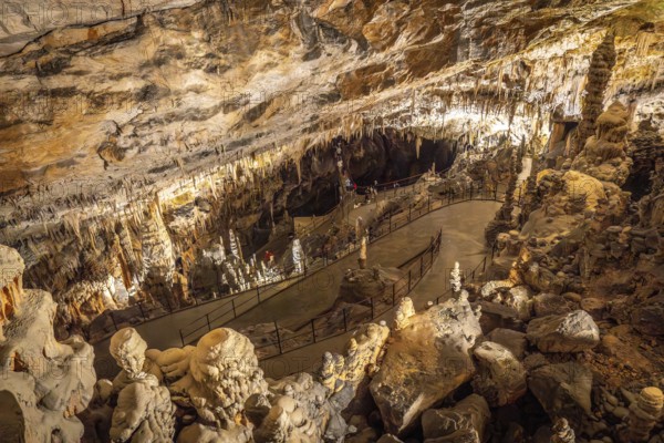 Tourists walking on illuminated footpath inside the famous postojna cave, a karst cave system near postojna, slovenia