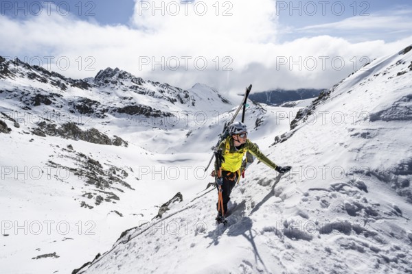 Mountaineer with skis climbing up a steep snow slope to the fork Porta d'Es-cha, ski tour Bündner Haute Route, Albula Alps, Rhaetian Alps, Grisons, Eastern Switzerland, Switzerland, Europe