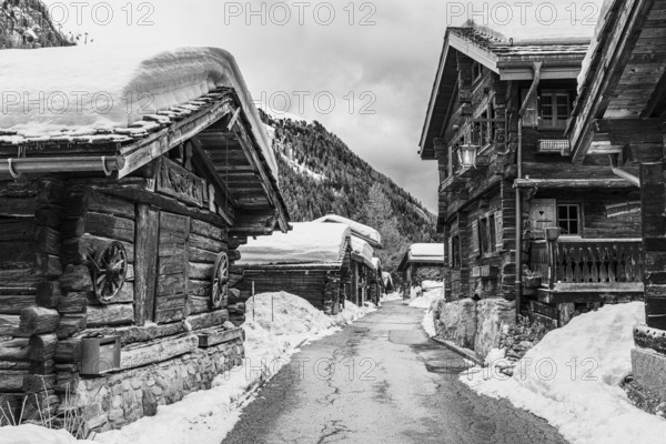 Street with historic old snow-covered wooden houses, black and white photo, mountain village Zinal, Val d'Anniviers, Valais Alps, Canton Valais, Switzerland, Europe