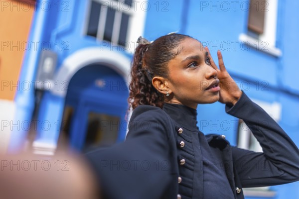 African american woman posing while taking selfie in the city next to blue colorful houses