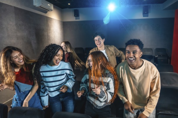 Happy multi ethnic friends dancing and celebrating together at a lively movie disco event in the cinema, enjoying every moment of fun