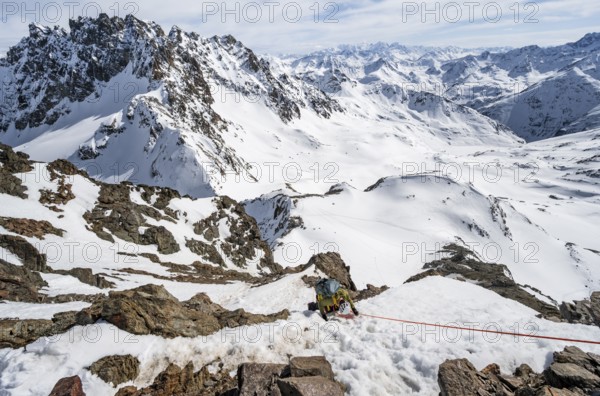 Mountaineer climbing up a steep snow slope, secured by a rope, ascent to the summit of Piz Grialetsch in winter, view of mountain panorama with Piz Vadret with snow, Grisons Haute Route, Albula Alps, Rhaetian Alps, Grisons, Switzerland, Europe