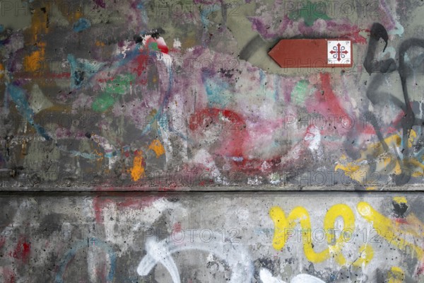 Graffiti-covered concrete wall with Olav's Cross signposting for pilgrims on the Olav Trail or Olavsleden, Oslo, Norway, Europe