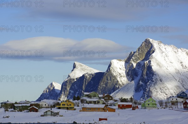 Colourful houses on snowy hills and mountains under a blue sky with few clouds, peaceful winter landscape, Ramberg, Flakstad, Lofoten, Nordland, Norway, Europe