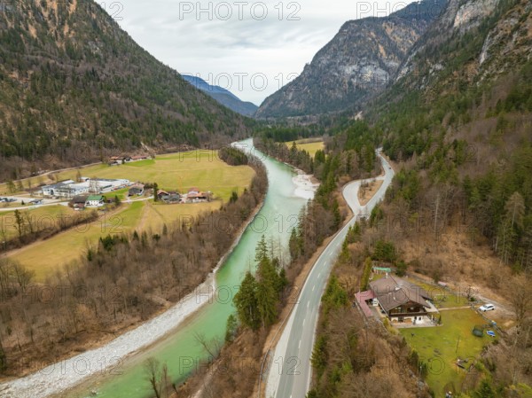 View of a river with a road leading through a green wooded area, surrounded by mountains and cloudy sky, Bad Reichenhall, Saalach, Bavaria, Germany, Europe