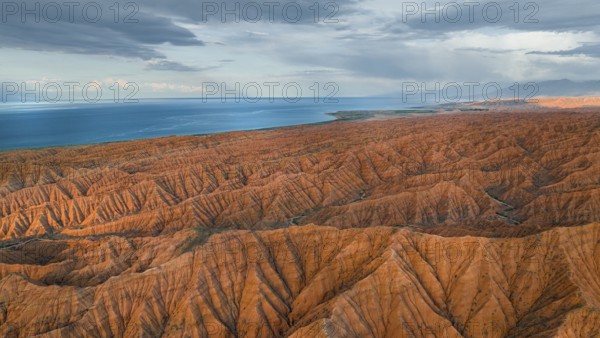 Landscape of eroded hills, badlands at sunset, Issyk Kul Lake in the background, aerial view, Canyon of the Forgotten Rivers, Issyk Kul, Kyrgyzstan, Asia