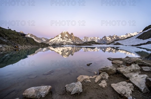 Evening mood with pink evening sky, mountain landscape with mountain hut Refuge du Lac Blanc at sunset, water reflection in Lac Blanc, mountain peaks Aiguille Verte and Grandes Jorasses of the Mont Blanc massif, Chamonix-Mont-Blanc, Haute-Savoie, France, Europe
