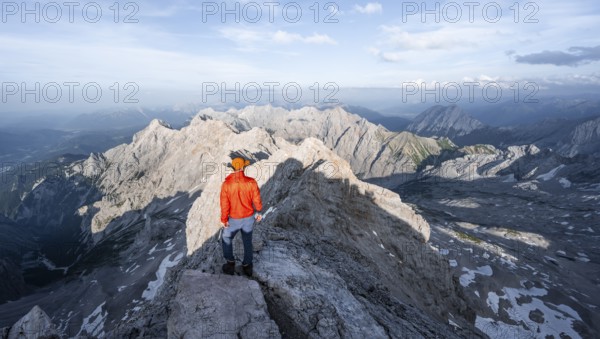 Mountaineer on a narrow rocky steep ridge, view of the Höllental and the Alpspitze from the Jubiläumsgrat, in the evening light Zugspitze, Wetterstein range, Bavaria, Germany, Europe
