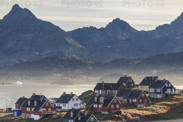 Typical Greenlandic houses on a fjord with steep mountains, Inuit settlement, autumn, Tasiilaq, East Greenland, Greenland, North America