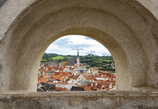 View of Ceský Krumlov town through a stone arch, featuring rooftops and church steeple, Cesky Krumlov, Czech Republic, Europe