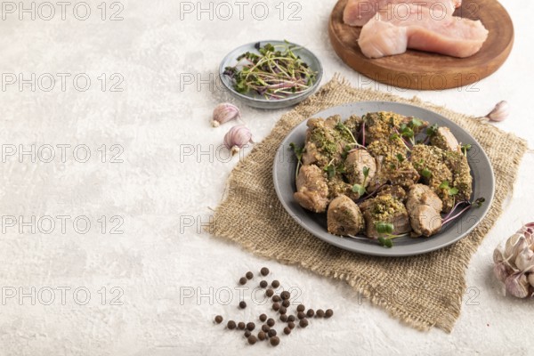 Stewed turkey fillet with garlic and sprouts of radish on white wooden background and linen textile. Side view, copy space