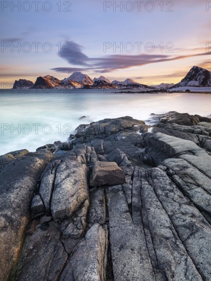 Rocky coast, snow-capped mountains in the background, Vestvågøya, Lofoten, Norway, Europe