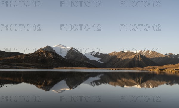 Glaciated mountain peaks reflected in a mountain lake at sunset, Arabel Lake at Arabel Pass, Issyk Kul Province, Kyrgyzstan, Asia