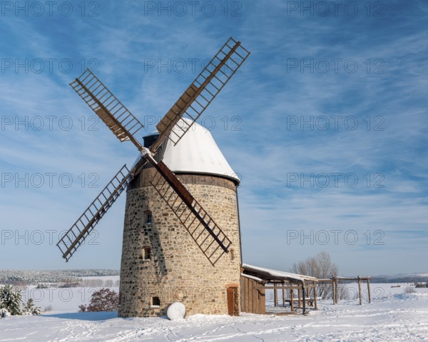 The tower windmill of Warnstedt in winter surrounded by snow-covered landscape under a blue sky, Teufelsmühle, Thale, Saxony-Anhalt, Germany, Europe